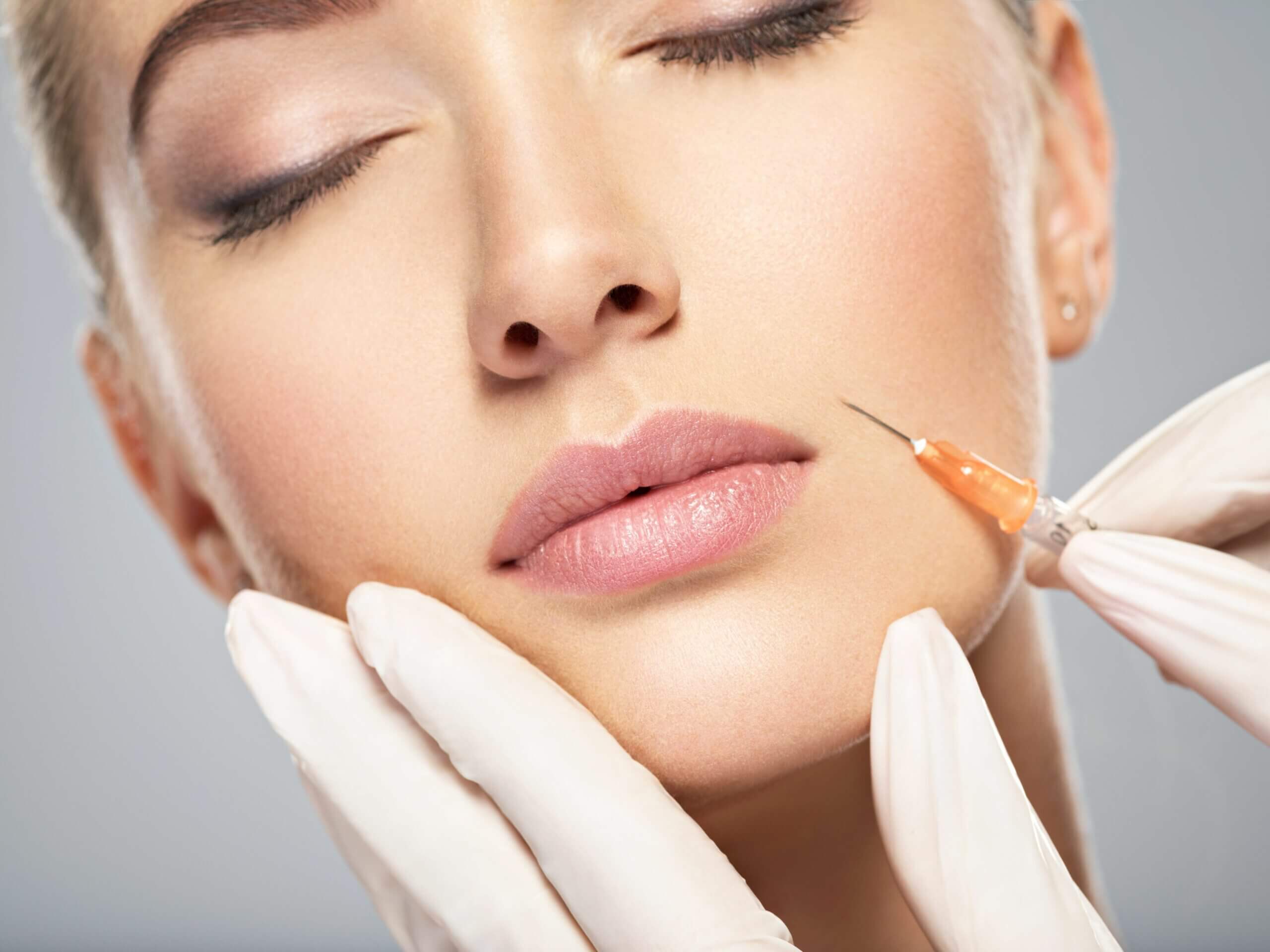 Young women taking Botox injection on face - Close up portrait of blonde woman with cosmetologist hands giving botox injection | Glow Wellness Care in East Northport, NY