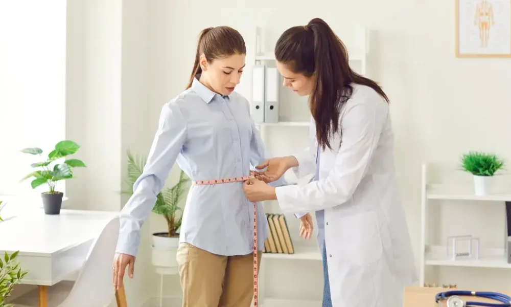 A healthcare professional measuring a woman's waist during a weight-loss consultation in Suffolk County, showing a semaglutide evaluation process